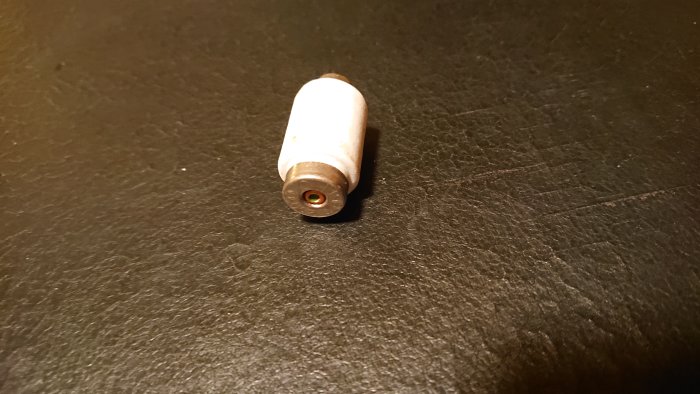 Gammal säkring med gänga för installation, märkt 10A - 1,5mm², ligger på en mörk yta.