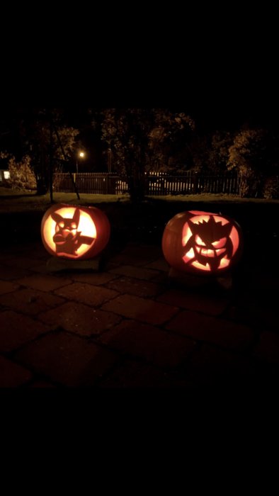 Två Halloween-pumpor utsmyckade som Pokémon-karaktärerna Pikachu och Gengar, lyser i mörkret.