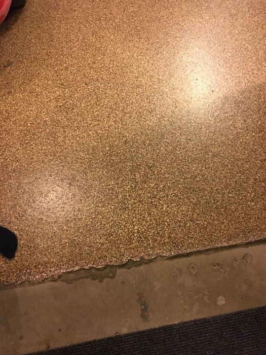 Golv med ytbehandling av klinker för att dölja sprickor, ojämn kant syns där behandlingen slutar.