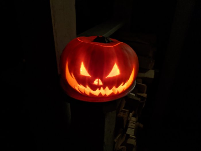 Upplyst klassisk halloweenpumpa med utskurna ögon och mun på mörk bakgrund.