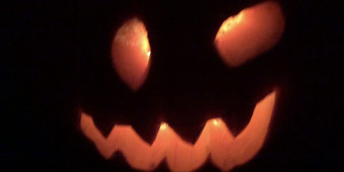 Upplyst halloweenpumpa med snidat leende ansikte i mörkret.