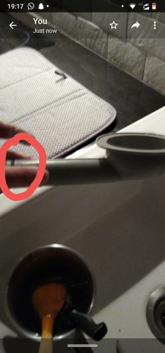 Vattenläcka under diskho markerad med röd cirkel, synlig vattenansamling och redskap i avloppet.