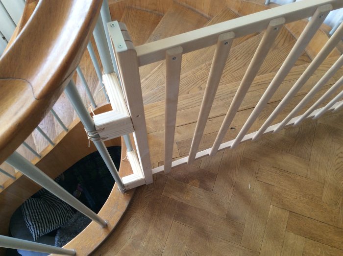 Hemmagjord trappskyddslösning med stålstänger fästa mellan två trästolpar vid en trätrappa.
