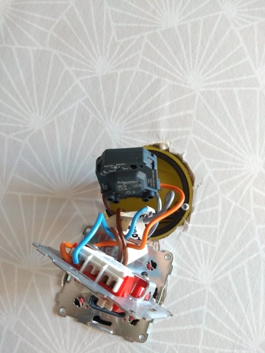 Elektrisk dosdimmer utan ram och knappar, med synliga ledningar och skruvar, redo för justering eller byte.