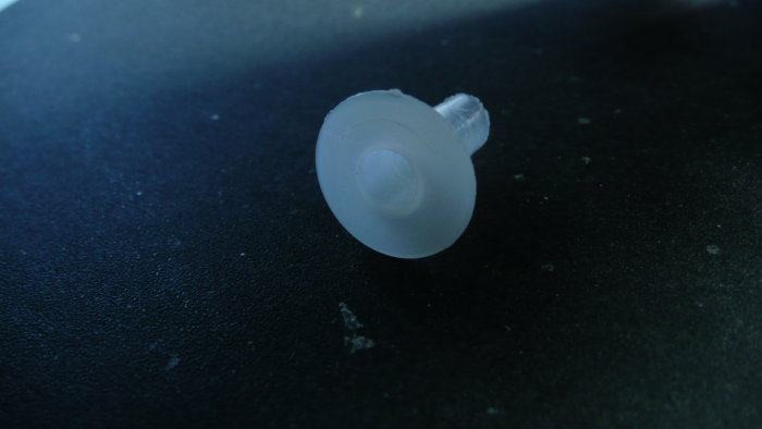 En vit isolersvamp som används för att skydda kablar i en lamphållare, placerad på en svart yta.