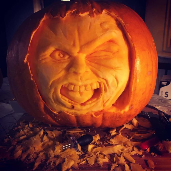 Uttalad halloweenpumpa med argt ansikte och verktyg för snideri runtomkring.