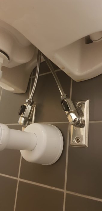 Väggbrickor med röranslutningar under handfat, inklusive ballofixventil och kopparledningar.