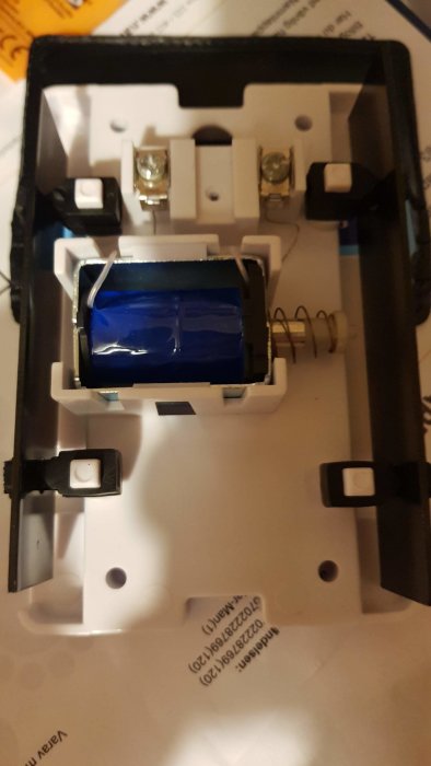 Insida av en ny ringklocka med två terminaler och ledningar redo för inkoppling.