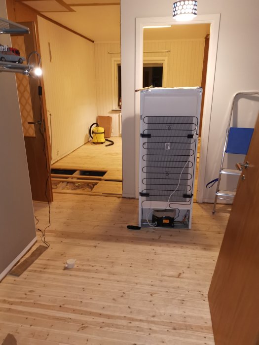 Renoveringsfas i hall med ommålad vägg, utspridda verktyg och en trappa.