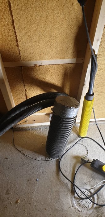 Svarta isolerade rör och kablar mot en vägg med isolering, tejpade och förberedda för installation.