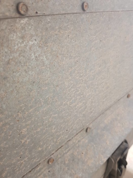 Närbild på härdad grussprut på släpvagnsskärm som behöver rengöras.