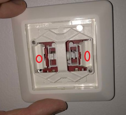 En hand pekar på en öppen eluttag med två röda ringar markerade på tryckmekanismen.