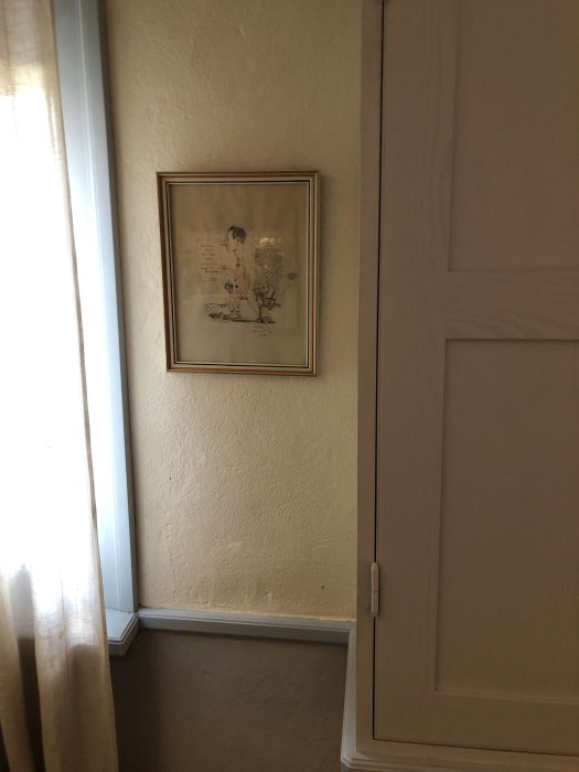 Vägg med kalkputs ovanför och under en mittelbandslist, inramad tavla och en del av en dörr.