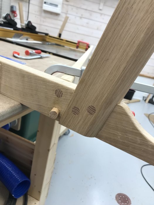 Träkonstruktion med flera plugghål i olika vinklar, tillverkad av ekmaterial i en verkstadsmiljö.