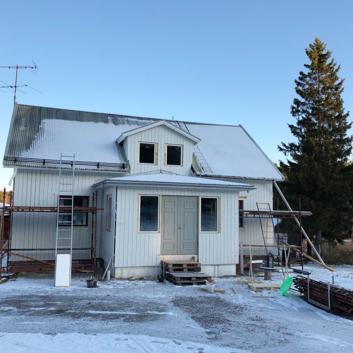 Nyinstallerade fönster och pardörrar på en husutbyggnad med snö på marken.