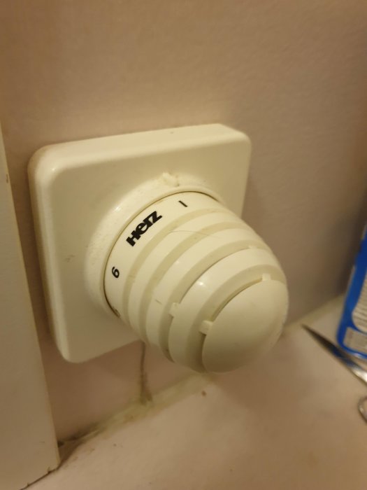 Vit termostatknopp märkt med "Heiz" på en väggplatta i ett badrum, synlig slitage och ingen synbar effekt vid vridning.
