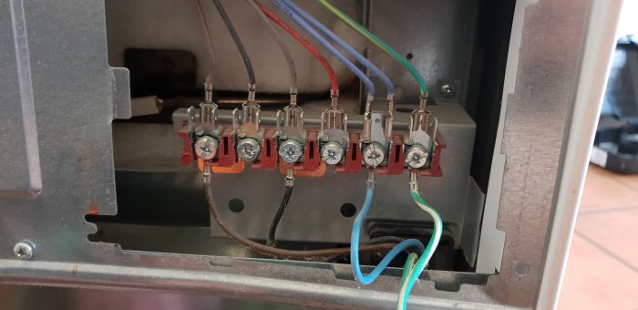 Öppet eluttag med flera färgade kablar och kontakter kopplade till terminaler, i ett köksrenoveringsprojekt.