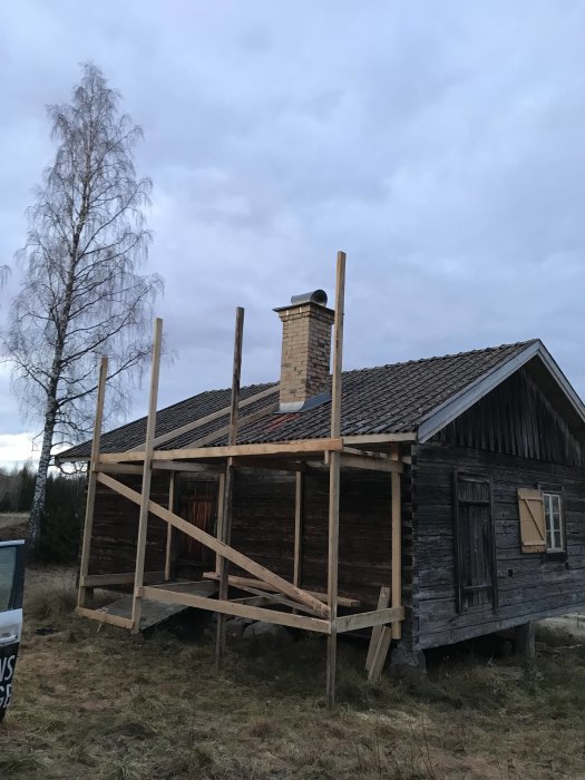 Ställning av trä runt en skorsten på ett gammalt trähus, förberett för nedmontering.