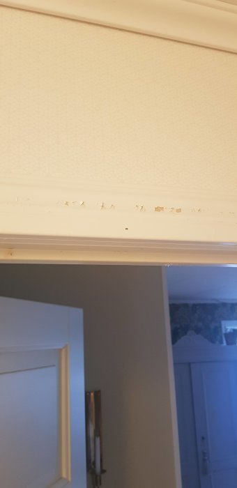 Fabriksmålad foder runt ett fönster med flagnande och sprucken färg.