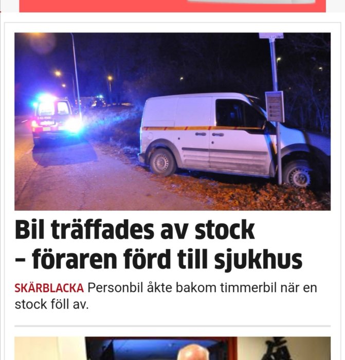 Vit skåpbil med skador står bredvid vägskylt, nödbelysning från polisbil i bakgrunden.