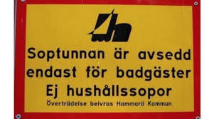 Röd och gul skylt med texten "Soptunnan är avsedd endast för badgäster Ej hushållssopor" samt kommunens namn.