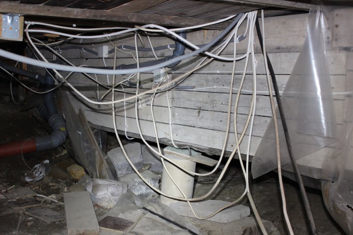 Oorganiserade elkablar under en byggnad innan en elektriker klamrade och märkte upp dem.