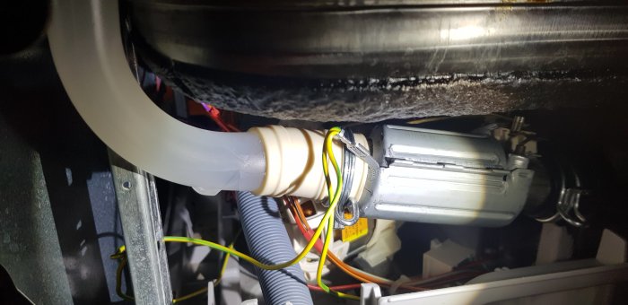 Diskmaskins inre med en läckande spolrör/stigningsrör nära värmeelementet.