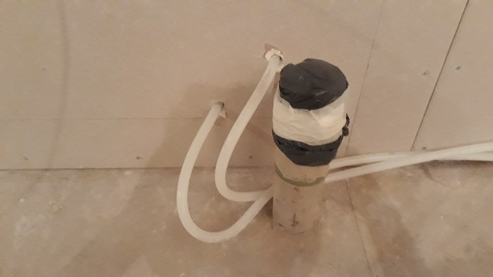 Draget pexrör genom en oisolerad innervägg under en köksrenovering.