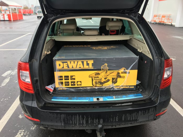 En ny DEWALT bordsåg i kartong lastad i bagageutrymmet på en bil.