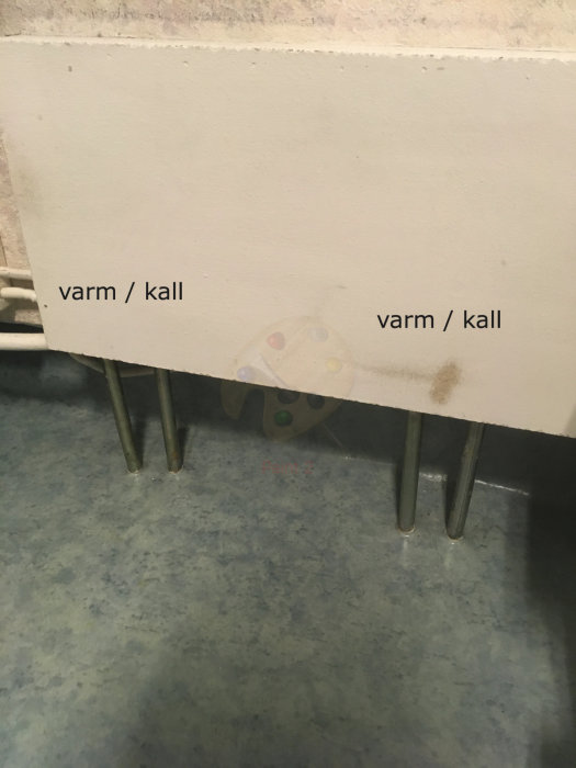 Värmesystems rör med etiketter "varm/kall" och en inställningsmekanism för flödet på en vägg.