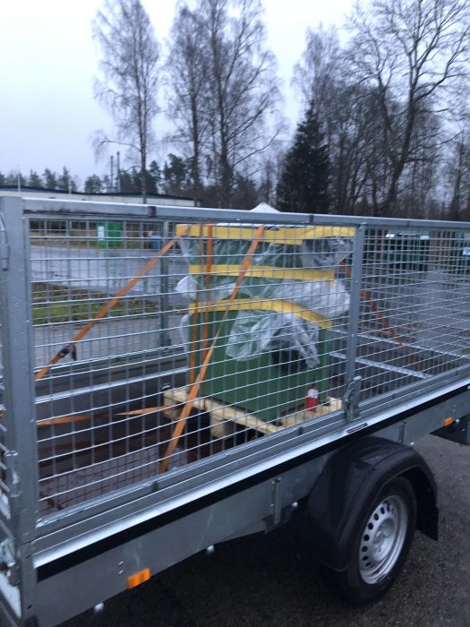 Ejca L28 vertikalfräs lastad på släpvagn, säkrad med spännband, träd och himmel i bakgrunden.