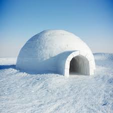 En igloo av snö mot en klarblå himmel på en solig dag.