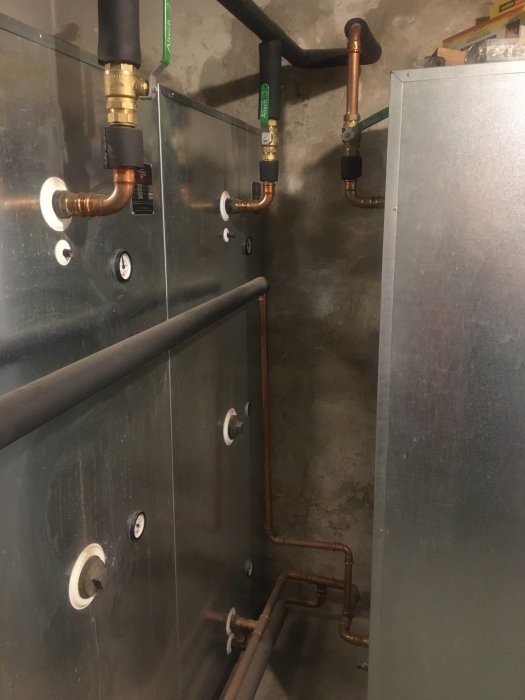 Ackumulatortank kopplad till rörsystem, synliga termometrar och mässingsbeslag.