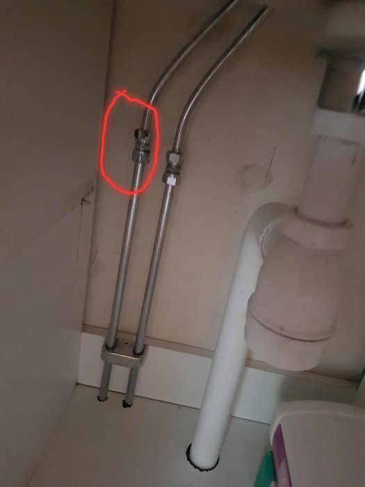 Läckande klämringskoppling markerad med rött på metallrör under diskho.