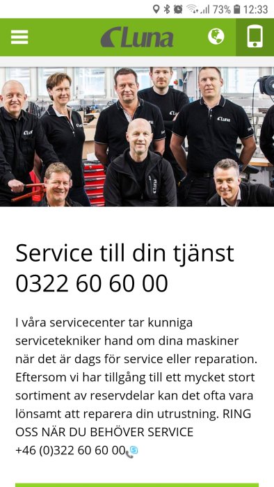 En grupp servicepersonal i arbetskläder poserar leende i en verkstad med Luna-logotypen.