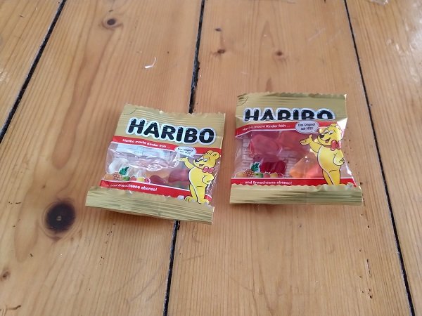 Två oöppnade påsar Haribo-godis på träplankor.