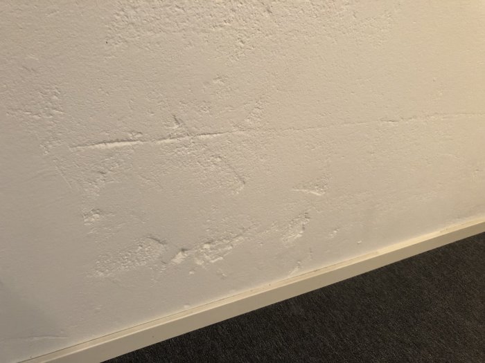 Vägg av lättbetong och puts med synliga gropar och skador som behöver repareras i ett renoveringsprojekt.