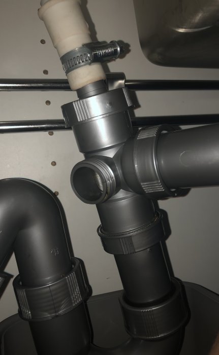 Avloppsrör under diskbänk med öppen inspektionsöppning där ett lock saknas.