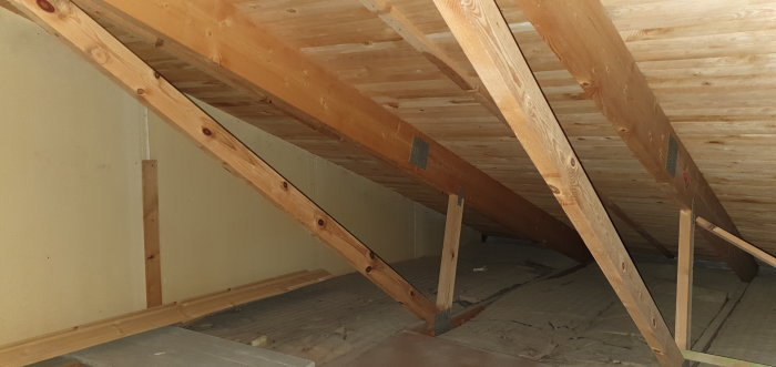 Inre syn på en vind med träbjälkar och takstolar som visar dimensioner nämnda i texten om renoveringsprojektet.