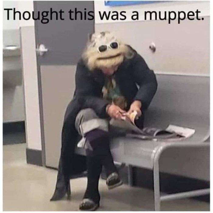 Person med ovanlig huvudbonad som påminner om en Muppet sitter och läser tidning.