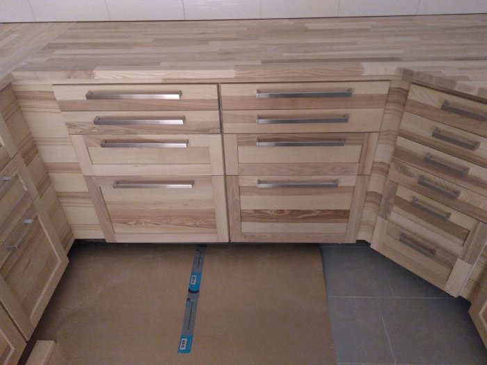 Nyinstallerade bänkskivor i kök med ljus träfinish och stålgrepp på lådorna.