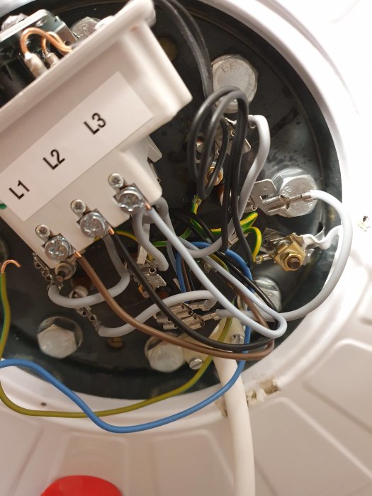 Elkopplingsområde inuti en värmeberedare med märkta terminaler L1, L2, L3 och anslutna kablar.