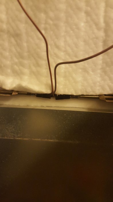 Bild av en öppen bakdel av en spis med elektriska anslutningar nära en stödplåt.