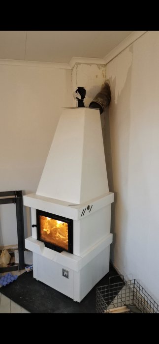 Kamin installerad i hörn med synlig eld, toppmonterat rökrör i 45 graders vinkel mot skorstenen.