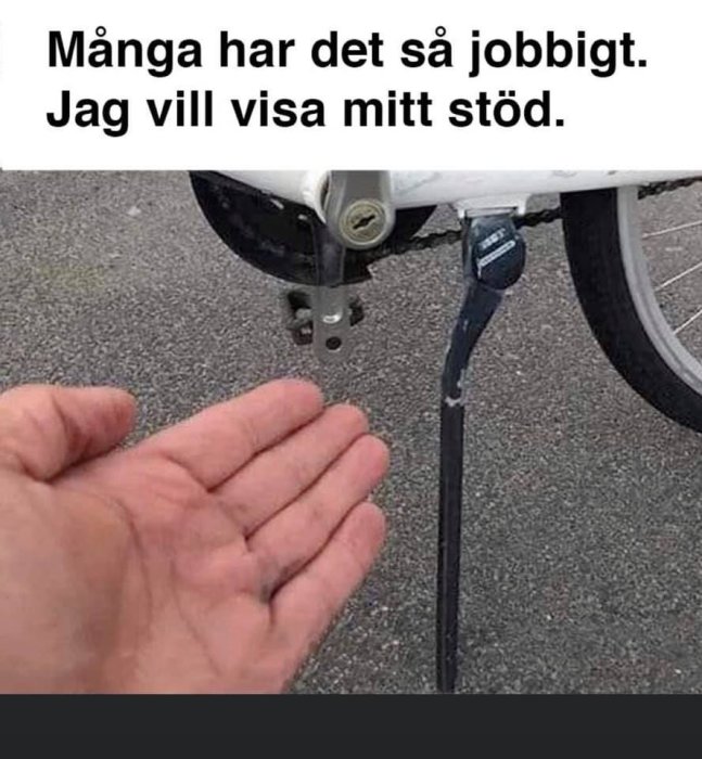 En hand framsträckt under ett cykelstöd, text säger "Många har det så jobbigt. Jag vill visa mitt stöd.