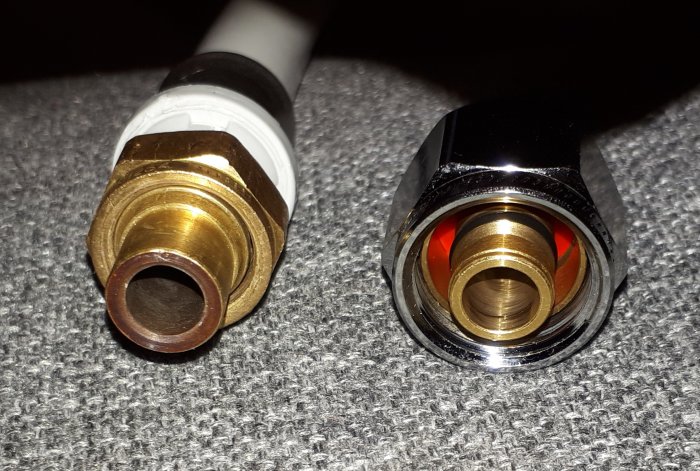 Brass fittings for plumbing, old one on the left and new one on the right, on fabric surface.