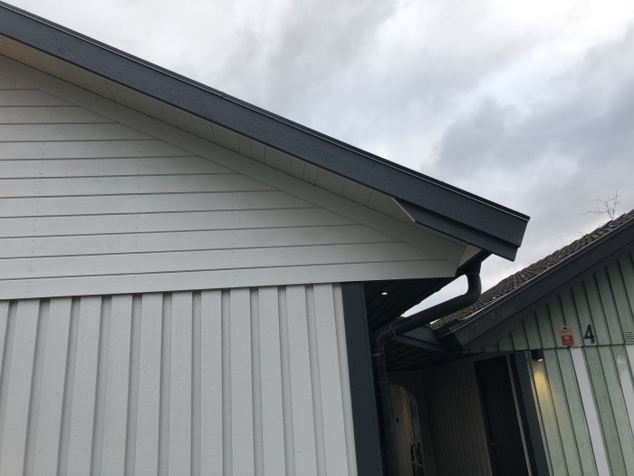 Husfasad med vindskiva och stupränna där en bräda saknas för att ansluta till vindskivan under.