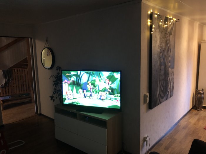 Vardagsrumsinteriör med TV på vägg och potentiell innervägg till höger, ifrågasatt om den är bärande.