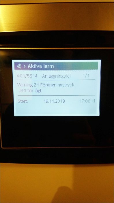 Display på en enhet som visar "Aktiva larm", ett felmeddelande om för lågt förändringstryck och startdatum.