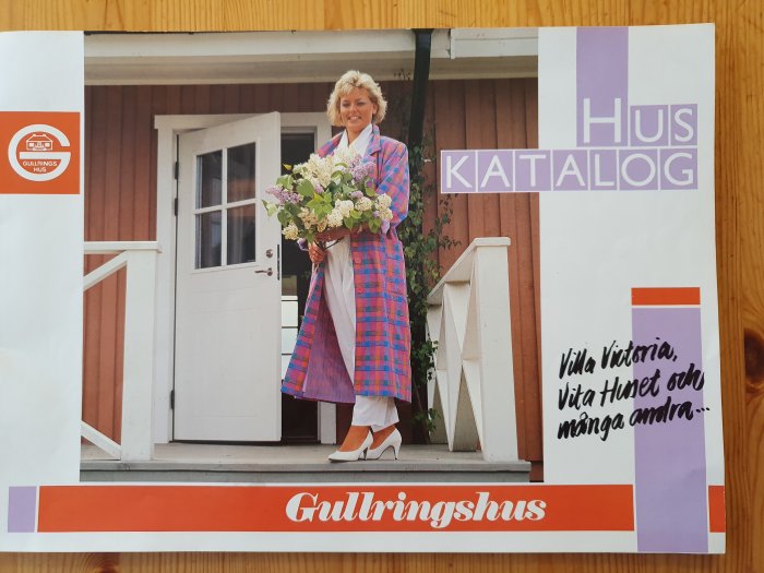 Kvinna med bukett blommor står på verandan på en bild från en huskatalog med texten "Villa Viktoria, Vita Huset och många andra".